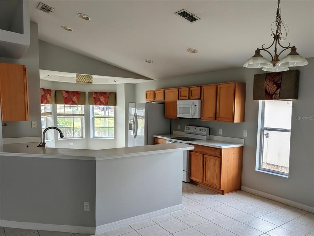 A kitchen with light wood cabinets, white countertops, a breakfast bar, and tile flooring — 732 HENLEY CIRCLE, DAVENPORT, FL