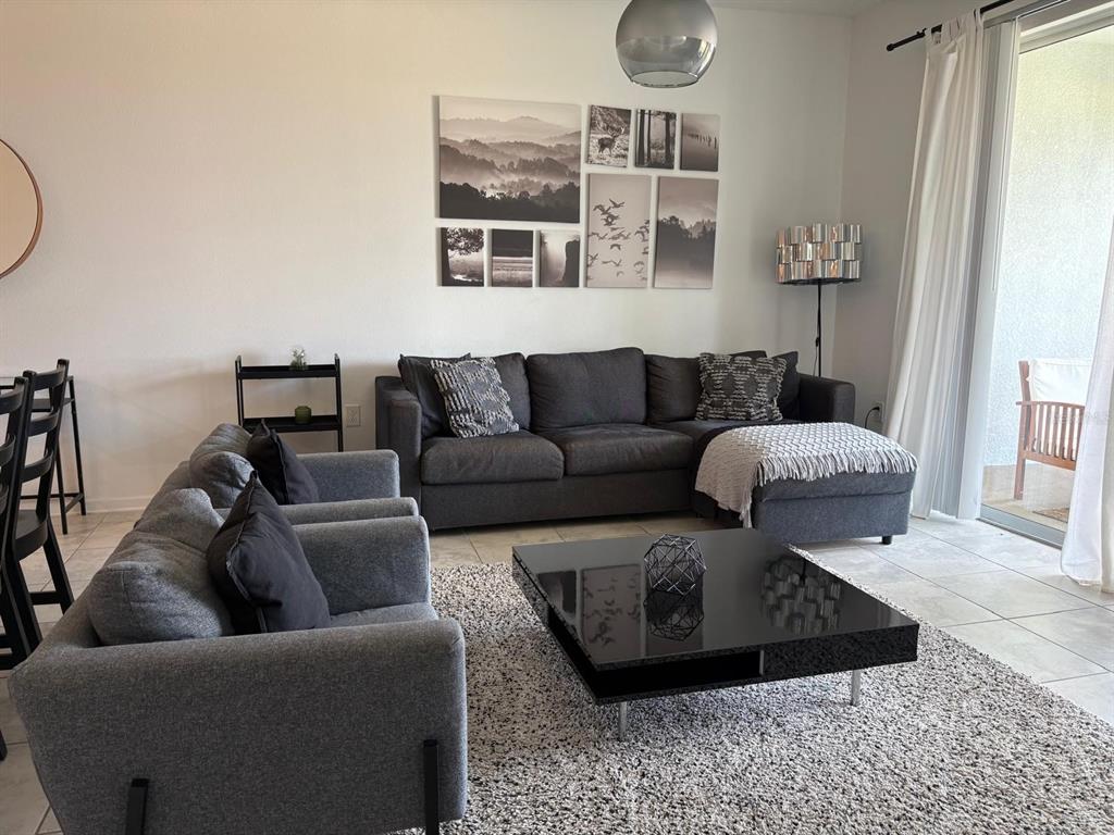 A living room features a gray sectional, matching armchair, black coffee table, and wall art — 993 SPLASH SHOT PLACE, DAVENPORT, FL