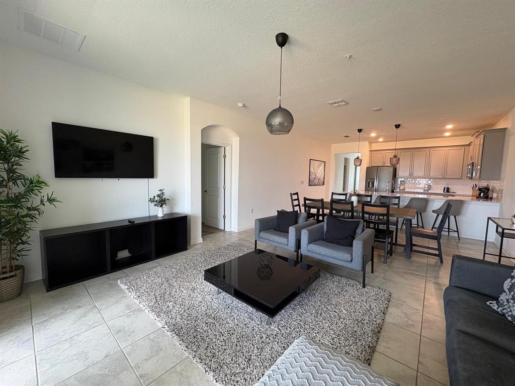 An open-concept living and dining area features tile flooring, a black coffee table, and cabinetry — 993 SPLASH SHOT PLACE, DAVENPORT, FL