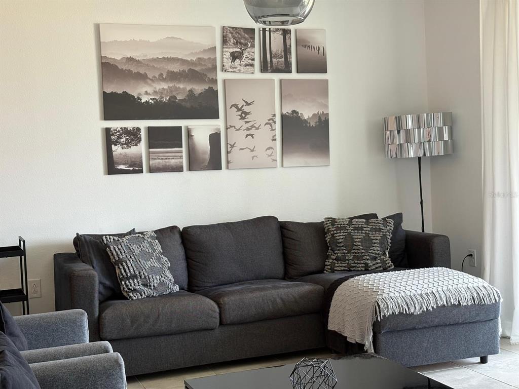 A living room features a dark gray sectional sofa, a coffee table, and a gallery wall — 993 SPLASH SHOT PLACE, DAVENPORT, FL