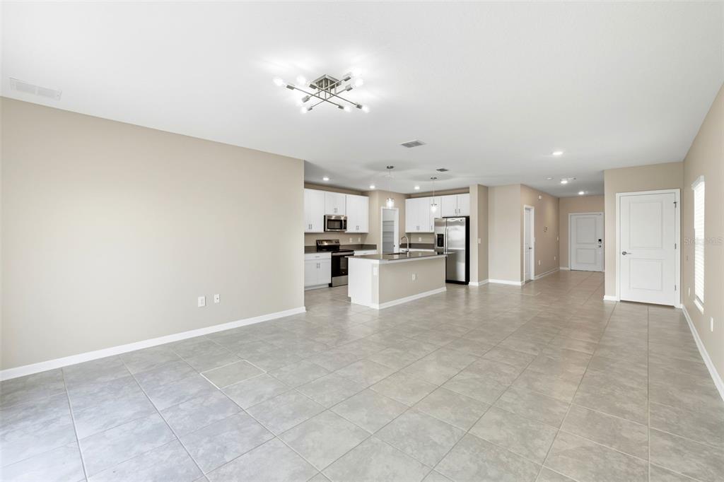 An open-concept kitchen with white cabinets and a center island overlooks a tiled living area — 724 DARING DRIVE, DAVENPORT, FL