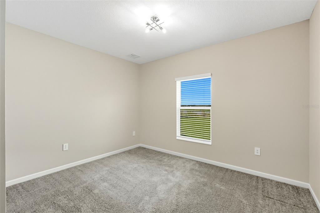 An empty bedroom with beige walls, gray carpet, a single window, and a ceiling light — 724 DARING DRIVE, DAVENPORT, FL