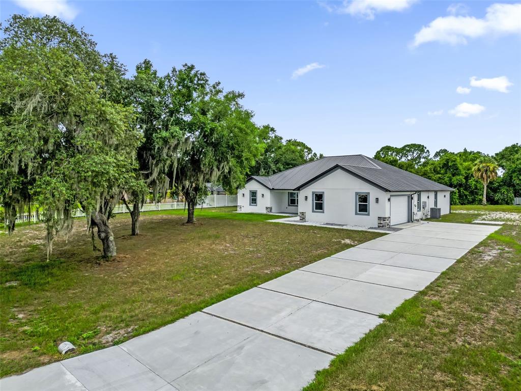 A white single-story house with a metal roof and a long concrete driveway — 2510 LAKE FRONT DRIVE, LAKE WALES, FL
