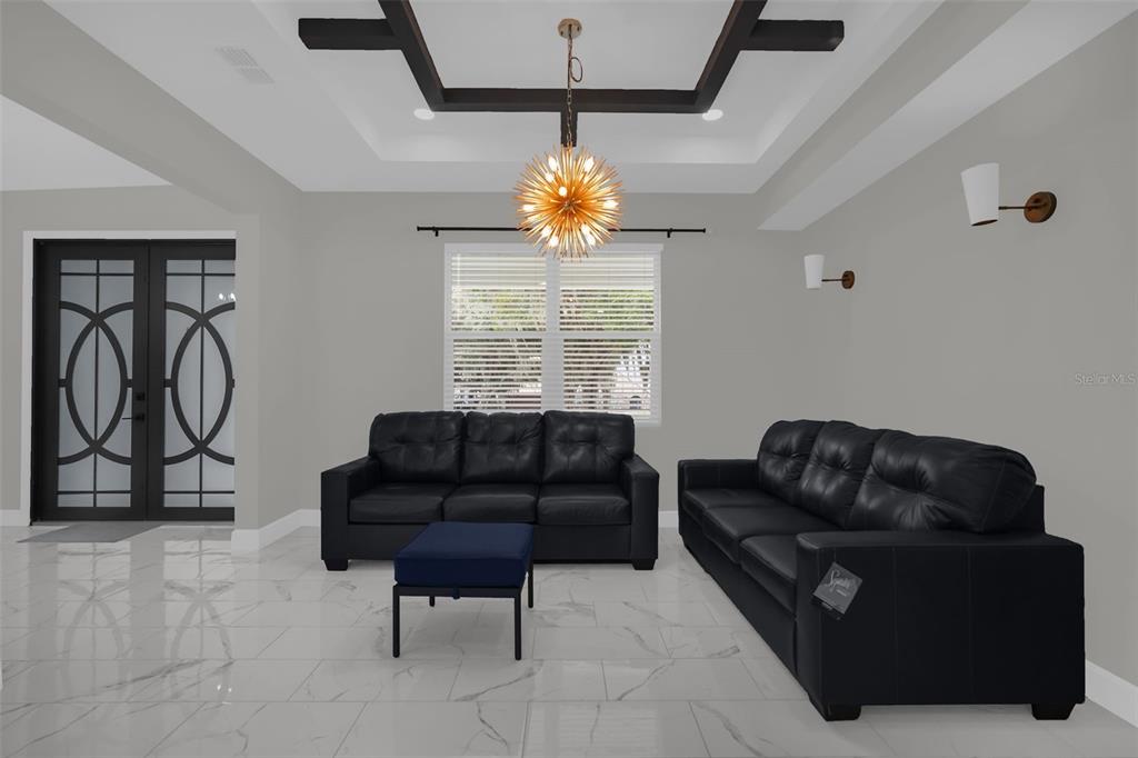 A living room features black leather sofas, a blue ottoman, and a modern sputnik chandelier — 2510 LAKE FRONT DRIVE, LAKE WALES, FL