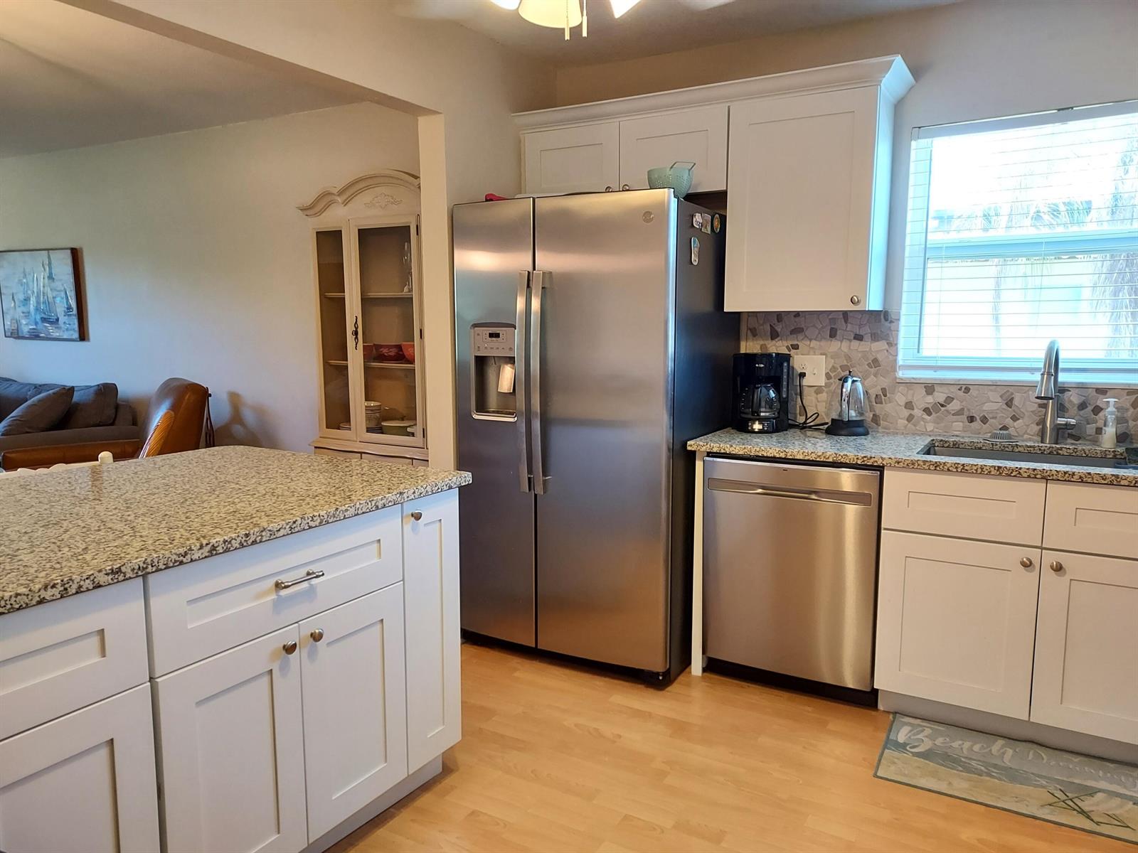 A kitchen features white cabinets, stainless steel appliances, granite countertops, and light wood flooring — 717 S Us Hwy 1 Unit 408, Jupiter FL 33477, JUPITER, FL