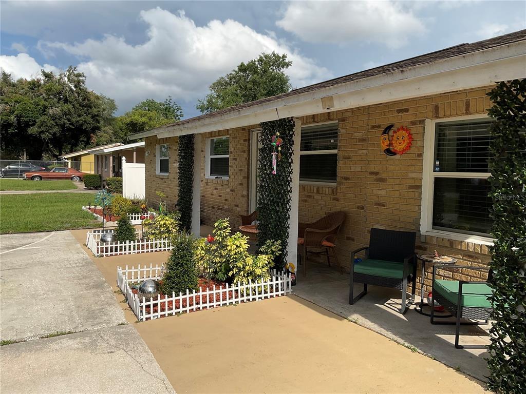 A brick house exterior features a covered porch, white picket fencing, and potted landscaping — 837 CAMPELLO STREET, ALTAMONTE SPRINGS, FL