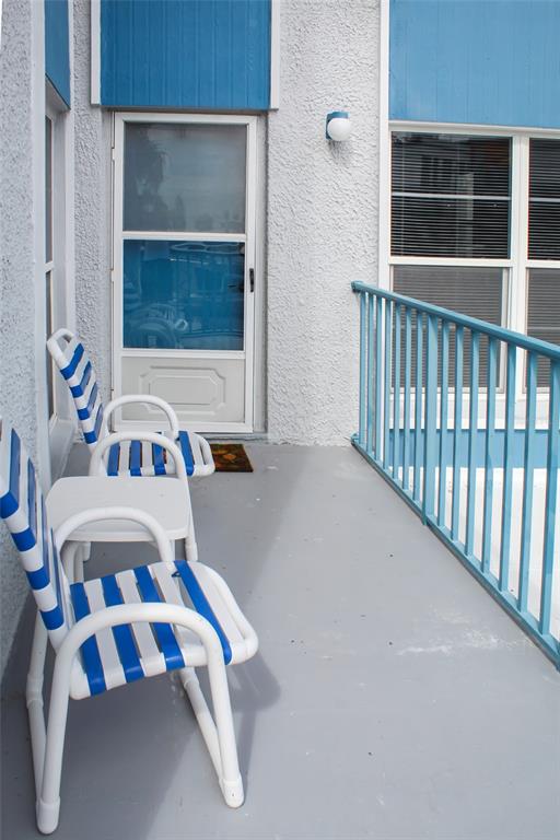 A balcony with two blue and white striped chairs, a small table, and blue railings — 215 MEDALLION BOULEVARD UNIT G, MADEIRA BEACH, FL