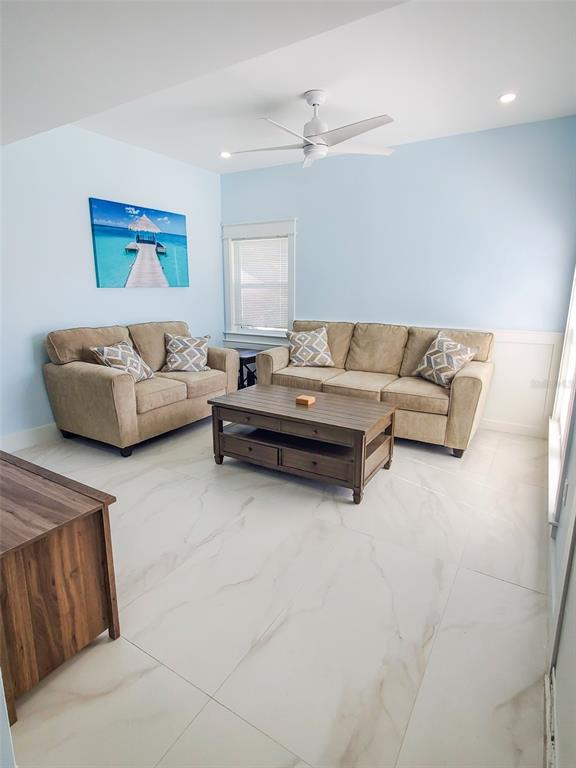 A living room features light blue walls, beige sofas, a wooden coffee table, and tile flooring — 215 MEDALLION BOULEVARD UNIT G, MADEIRA BEACH, FL