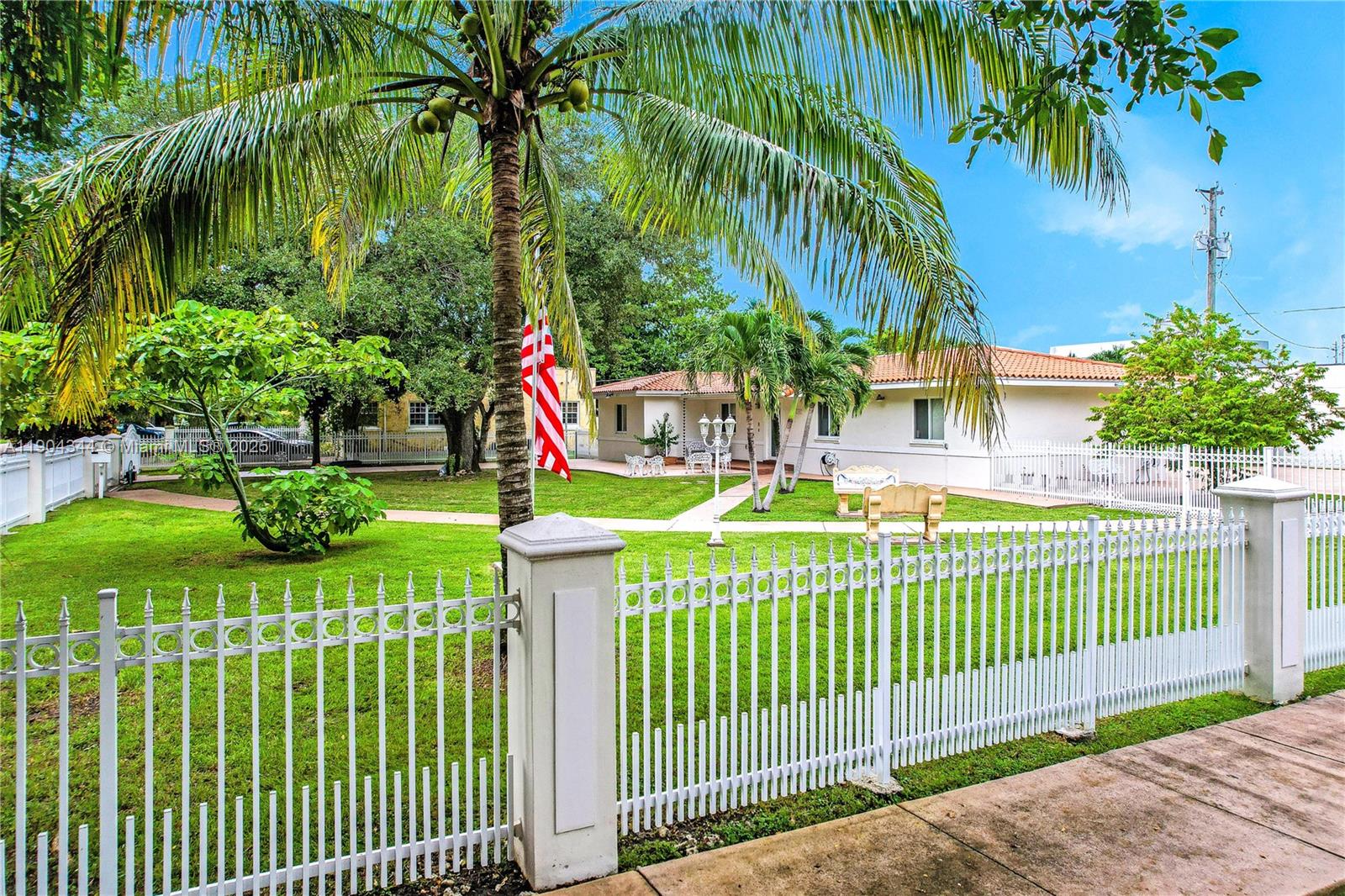 A single-story house with a white fence and a palm tree in the front yard — 1407 San Marco Ave, Coral Gables FL 33134, CORAL GABLES, FL
