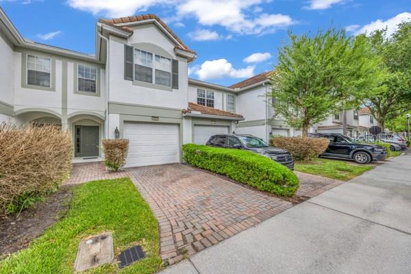A two-story townhouse with a brick driveway, white siding, and a two-car garage — 6924 HOCHAD DRIVE, ORLANDO, FL