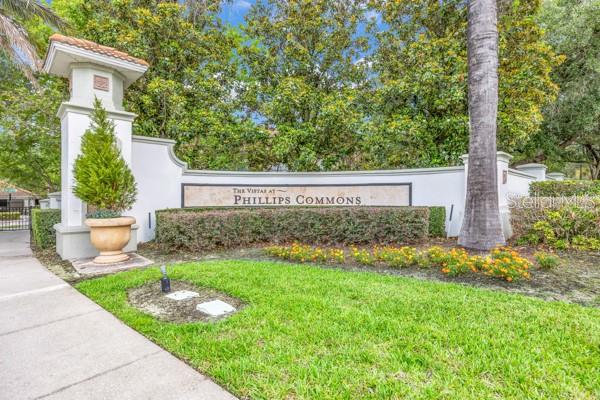 The entrance sign for The Vistas at Phillips Commons stands beside a sidewalk and lawn — 6924 HOCHAD DRIVE, ORLANDO, FL