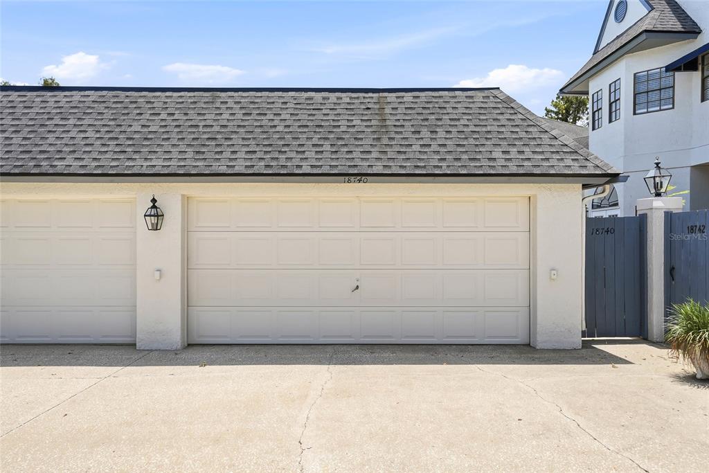 A view of a two-car garage exterior with a shingled roof and concrete driveway — 18740 WIMBLEDON CIRCLE, LUTZ, FL
