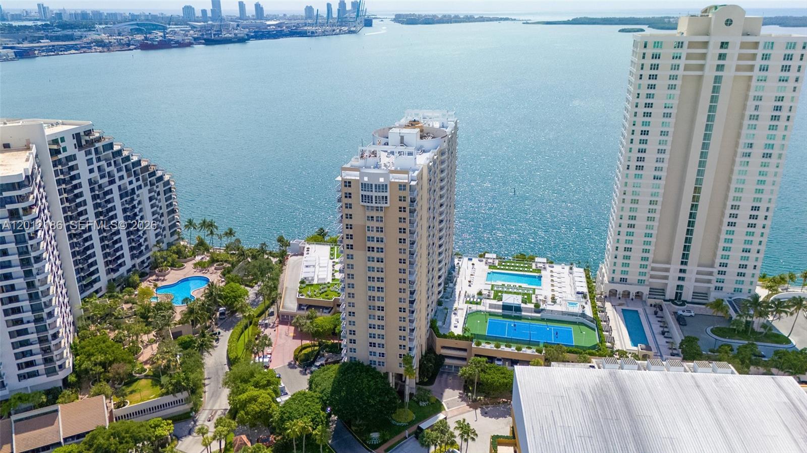 An aerial view shows three high-rise residential buildings with pools and a tennis court — 770 Claughton Island Dr # 1114, Miami FL 33131, MIAMI, FL