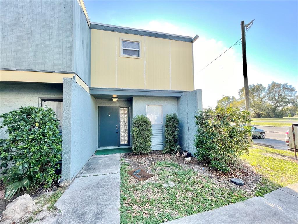 The exterior of a two-story townhouse features a teal front door and light-colored siding — 719 SW 75TH STREET UNIT 103, GAINESVILLE, FL
