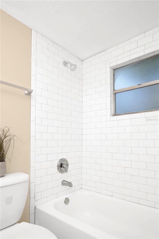 A bathroom features a white subway-tiled shower surround, a bathtub, and a frosted window — 847 JASMINE AVENUE, HOLLY HILL, FL