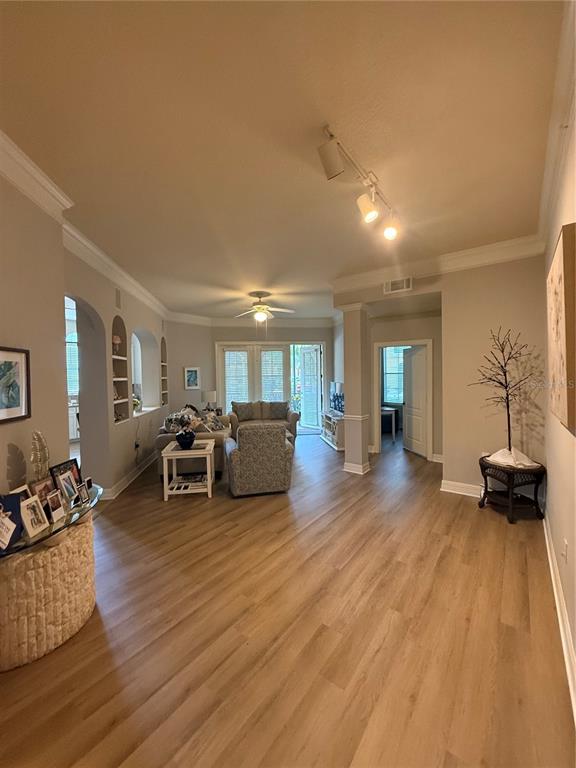 A living room with light wood-look flooring, recessed shelving, and a ceiling fan — 515 MIRASOL CIRCLE UNIT 101, CELEBRATION, FL