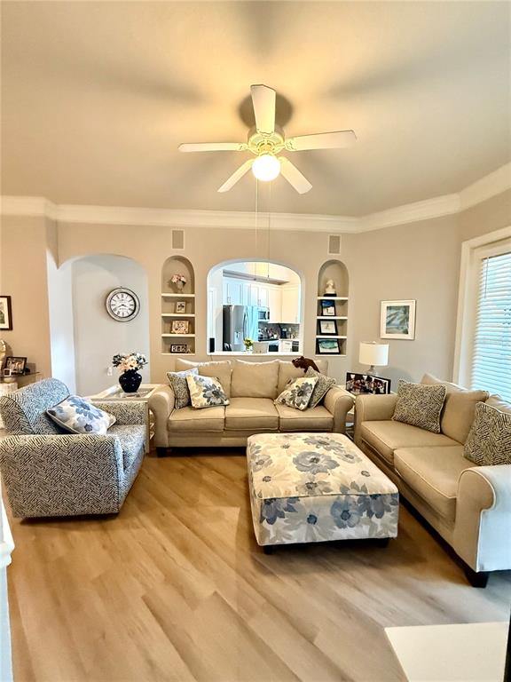 A living room features light wood flooring, a ceiling fan, and built-in arched shelving — 515 MIRASOL CIRCLE UNIT 101, CELEBRATION, FL