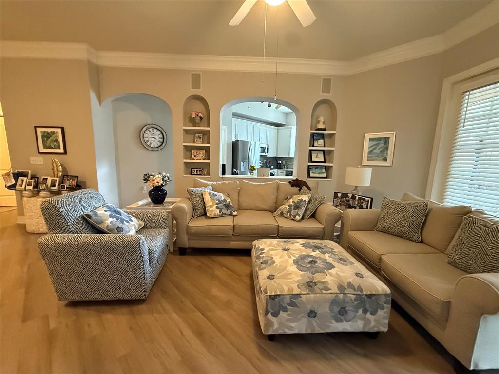 A living room features light wood flooring, beige sofas, a patterned armchair, and built-in shelving — 515 MIRASOL CIRCLE UNIT 101, CELEBRATION, FL
