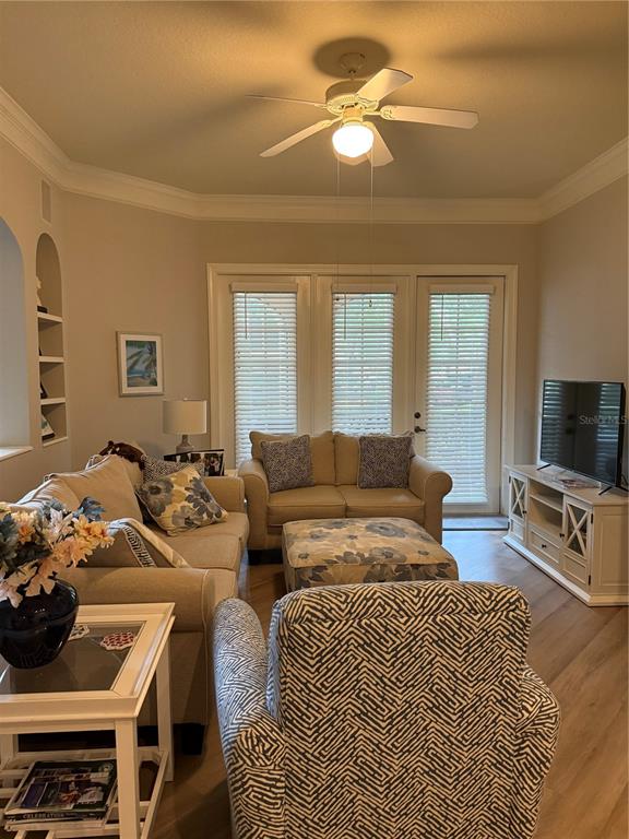 A living room features a ceiling fan, beige sofa, patterned armchair, and a television console — 515 MIRASOL CIRCLE UNIT 101, CELEBRATION, FL