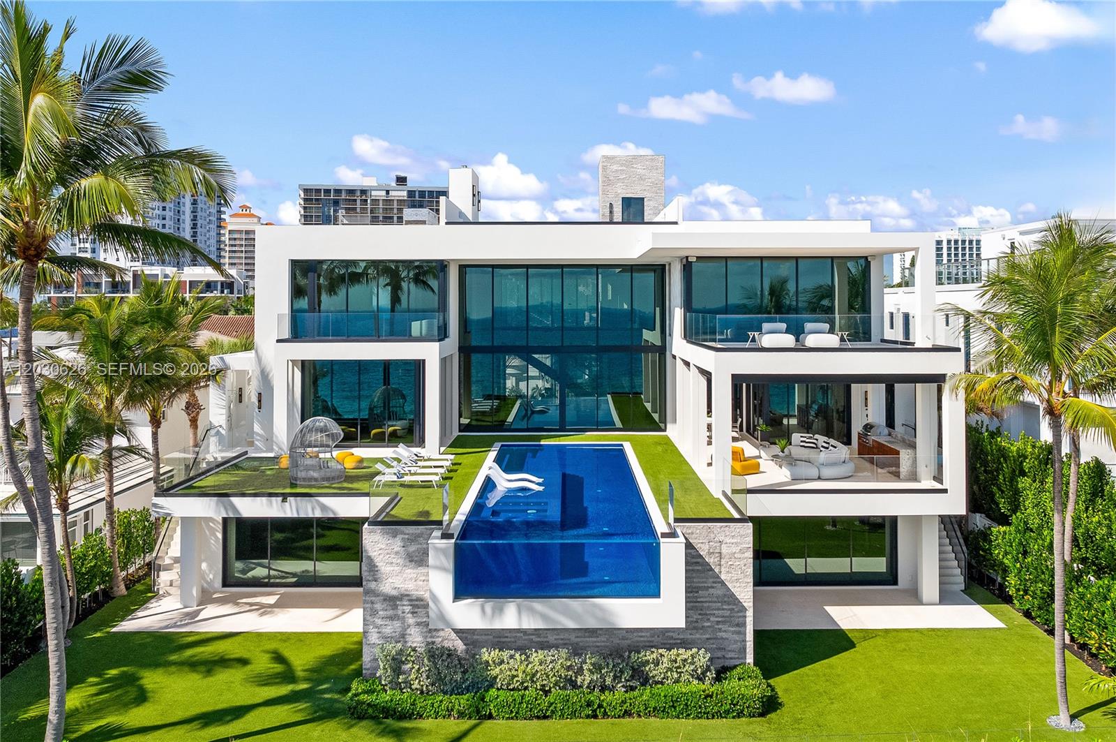 A modern multi-story waterfront home features a glass-walled infinity pool and expansive outdoor terraces — FORT LAUDERDALE, FL