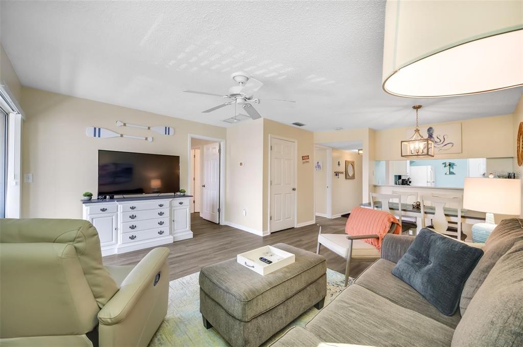 A living room features a television on a white cabinet, a sofa, and an ottoman — 260 MEDALLION BOULEVARD UNIT F, MADEIRA BEACH, FL