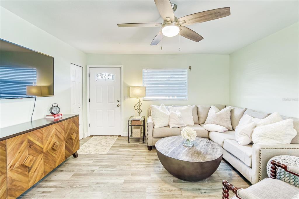 A living room features a sectional sofa, a wooden media console, and a ceiling fan — 6004 GOLF AND SEA BOULEVARD, APOLLO BEACH, FL