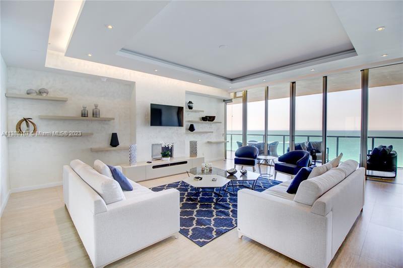 A modern living room features two white sofas, a patterned rug, and floor-to-ceiling ocean views — 9705 Collins Ave # 1003N, Bal Harbour FL 33154, BAL HARBOUR, FL