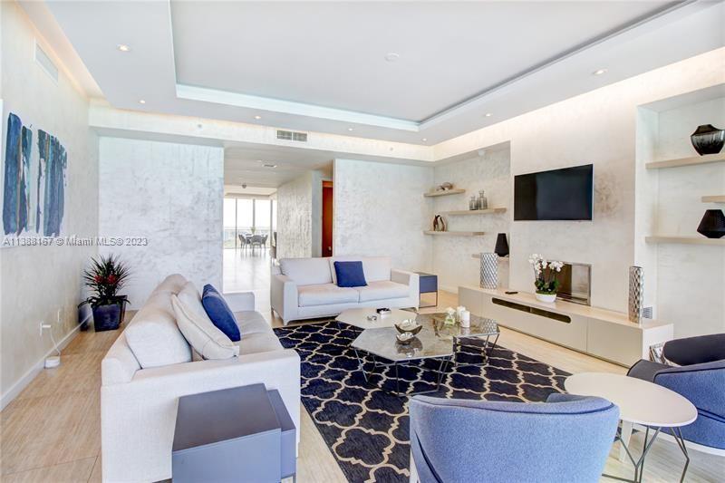 A modern living room features a white sofa, blue armchairs, and a patterned area rug — 9705 Collins Ave # 1003N, Bal Harbour FL 33154, BAL HARBOUR, FL
