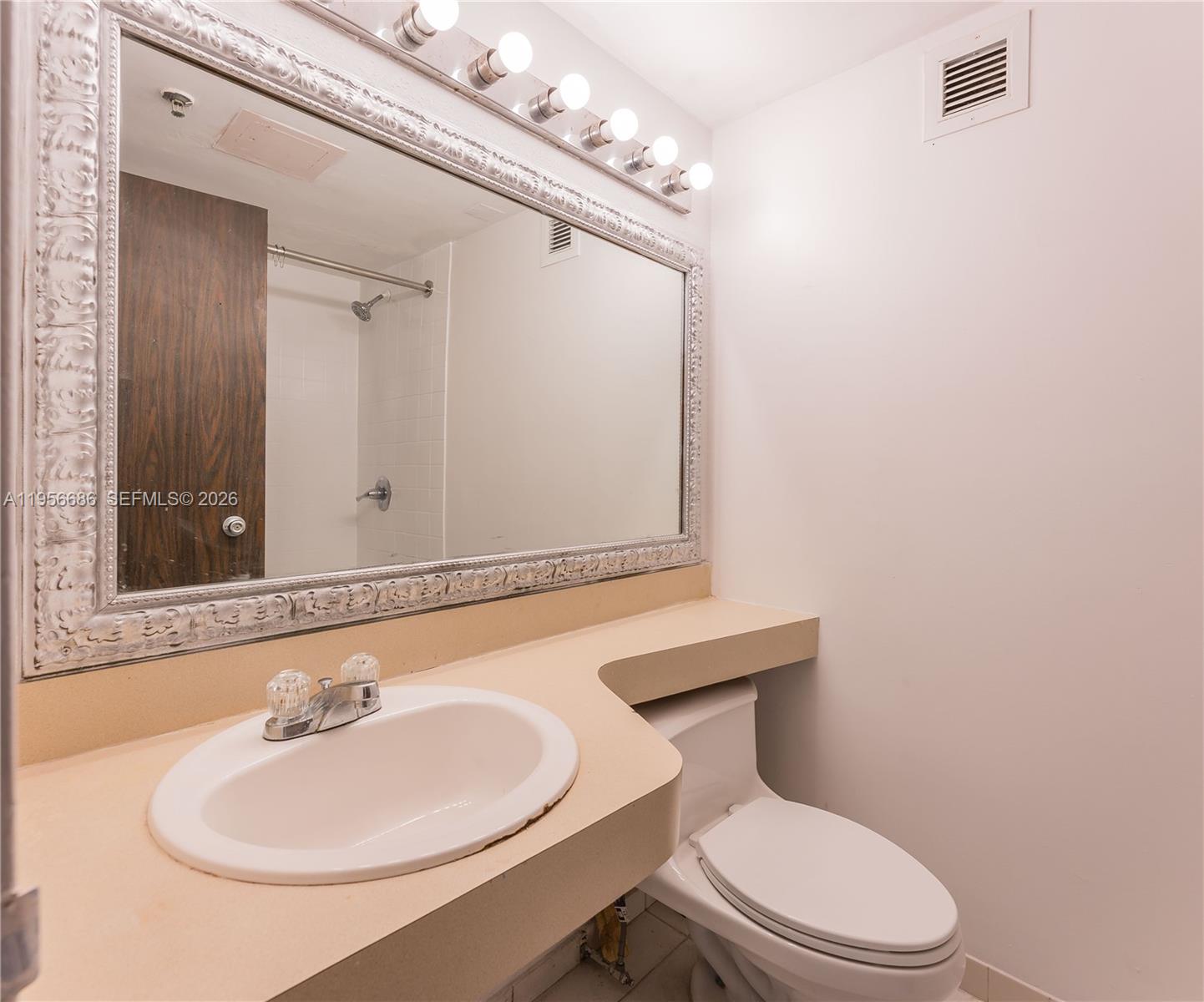 A bathroom features a beige vanity, a large ornate mirror, and a white toilet — 16450 NW 2nd Ave # 103, Miami FL 33169, MIAMI, FL