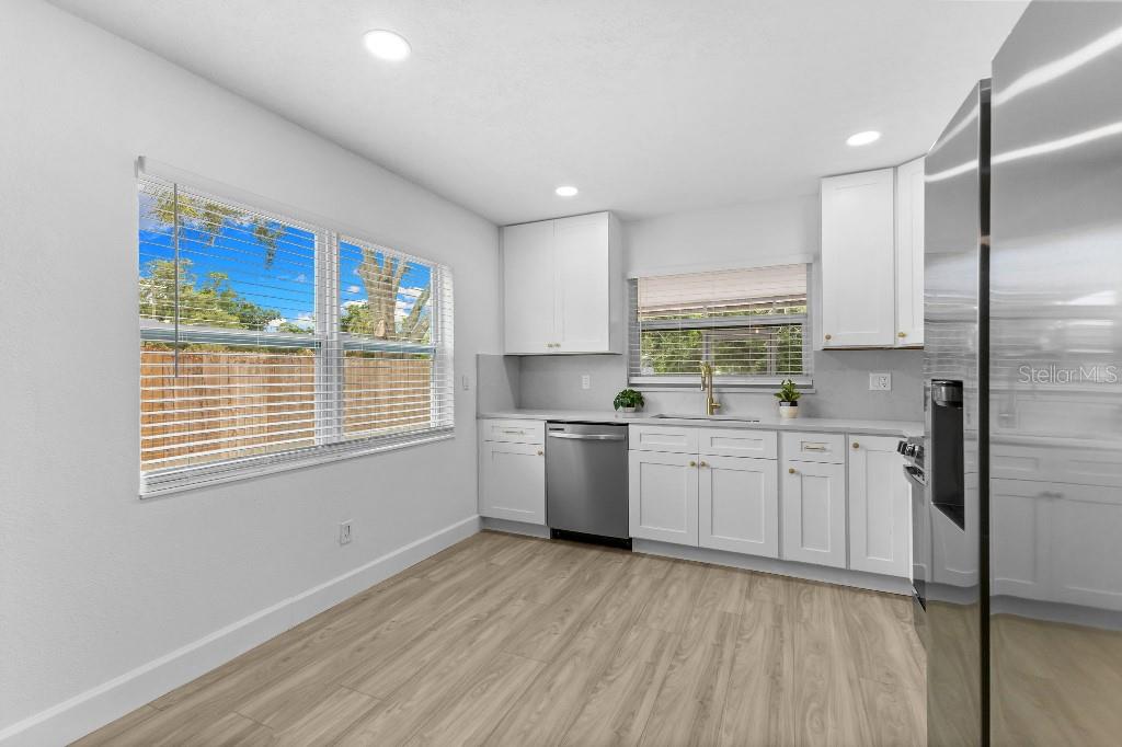 A kitchen with white cabinets, stainless steel appliances, light wood-look flooring, and two windows — 5690 25TH STREET CIRCLE E, BRADENTON, FL