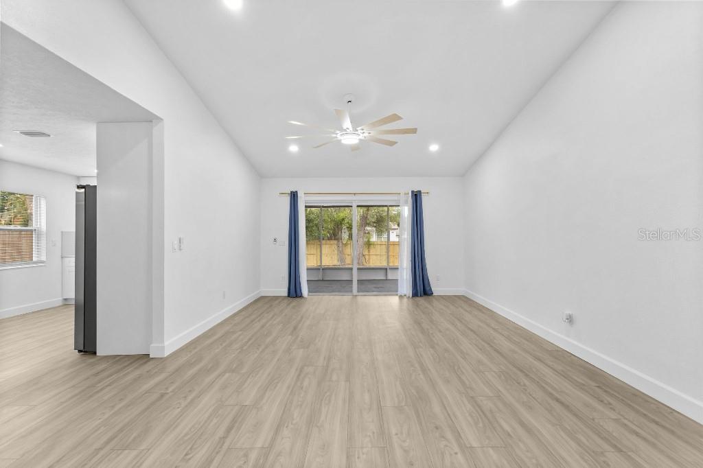 A bright living room with light wood-look flooring, a ceiling fan, and sliding glass doors — 5690 25TH STREET CIRCLE E, BRADENTON, FL