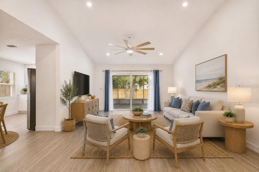 A bright living room with light wood flooring, a sofa, two chairs, and sliding doors — 5690 25TH STREET CIRCLE E, BRADENTON, FL