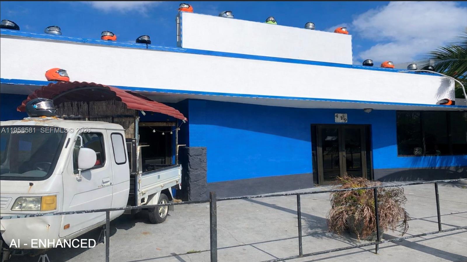 A white and blue commercial building features a row of motorcycle helmets along its roofline — 419 NW 79th St, Miami FL 33150, MIAMI, FL