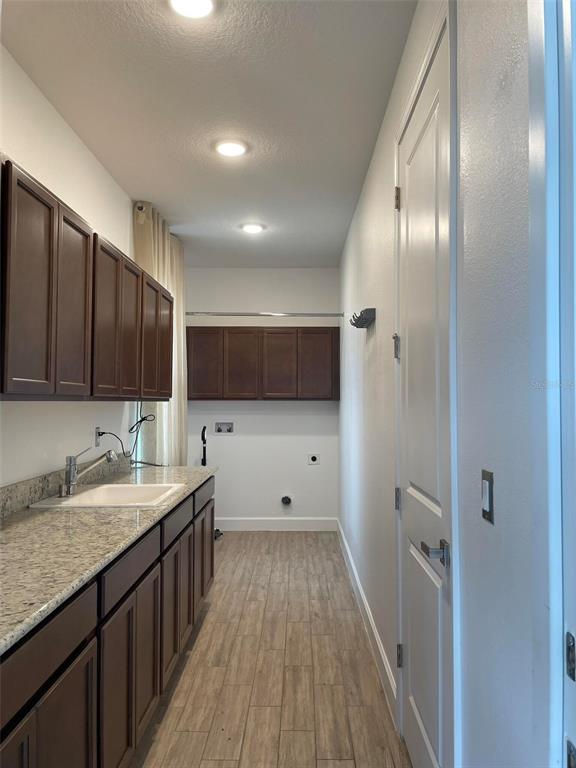 A laundry room features dark wood cabinets, granite countertops, a sink, and tile flooring — 17708 SAWGRASS RUN, DEER ISLAND, FL