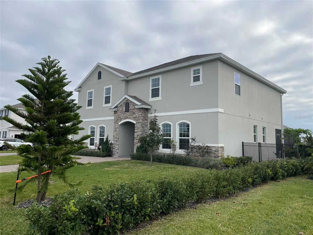 A two-story house with a stone-accented entryway, grey stucco siding, and a manicured lawn — 17708 SAWGRASS RUN, DEER ISLAND, FL