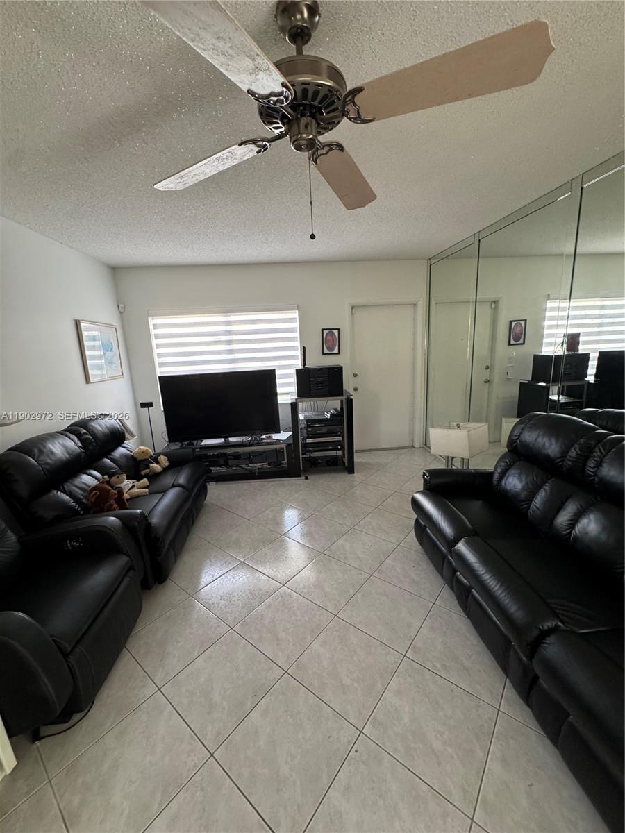 A living room features two black leather sofas, tiled floors, a ceiling fan, and mirrored walls — 1501 Arthur St # 1, Hollywood FL 33020, HOLLYWOOD, FL