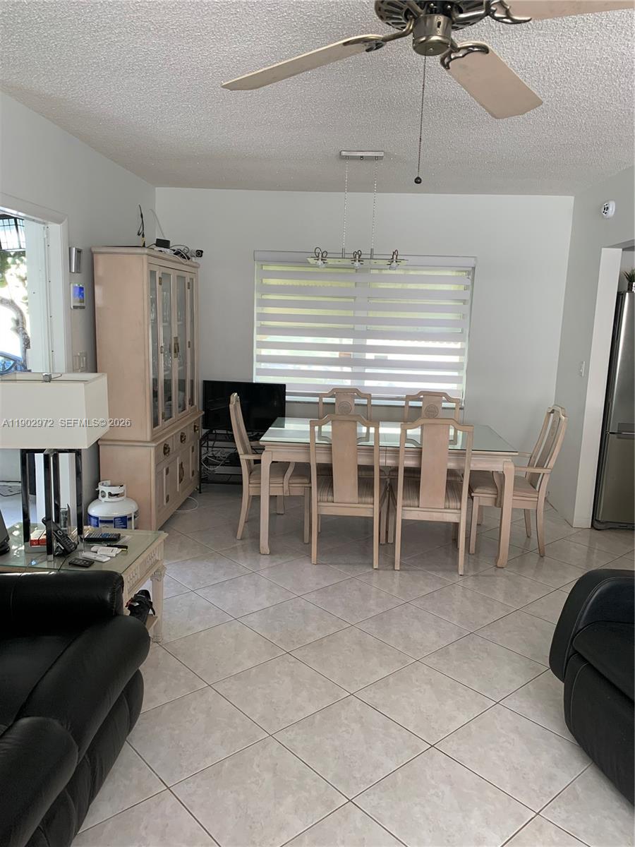 A dining area features a glass-topped table, six chairs, a china cabinet, and tile flooring — 1501 Arthur St # 1, Hollywood FL 33020, HOLLYWOOD, FL