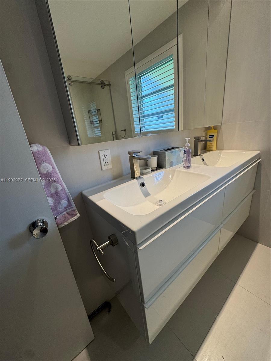 A modern bathroom features a double-sink vanity with white cabinets and a mirrored medicine cabinet — 1501 Arthur St # 1, Hollywood FL 33020, HOLLYWOOD, FL