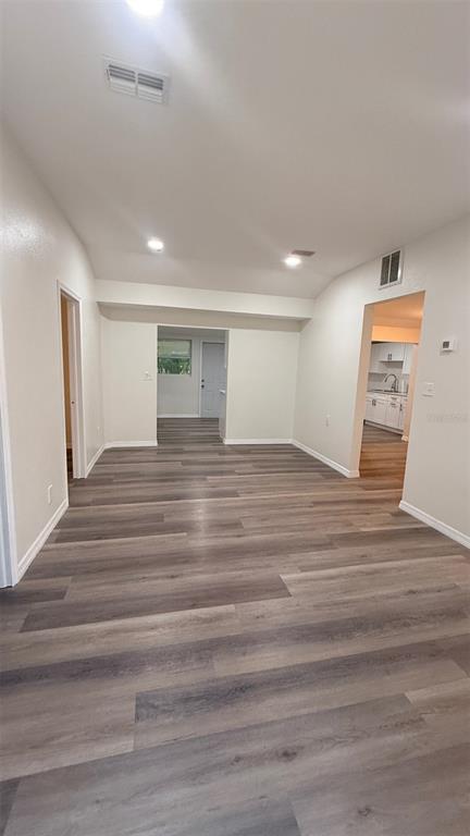An interior view shows a living area with wood-look flooring leading to a kitchen doorway — 15535 LITTLE RANCH ROAD, SPRING HILL, FL