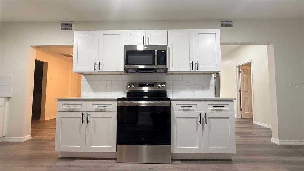 A kitchen features white shaker cabinets, stainless steel appliances, and a white subway tile backsplash — 15535 LITTLE RANCH ROAD, SPRING HILL, FL