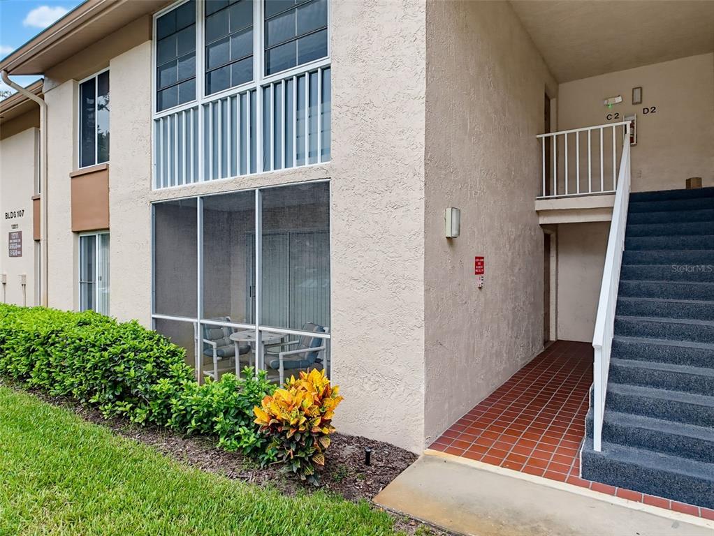 Exterior view of a two-story apartment building with a screened patio and outdoor staircase — 12211 FOX CHASE DRIVE UNIT C1, HUDSON, FL