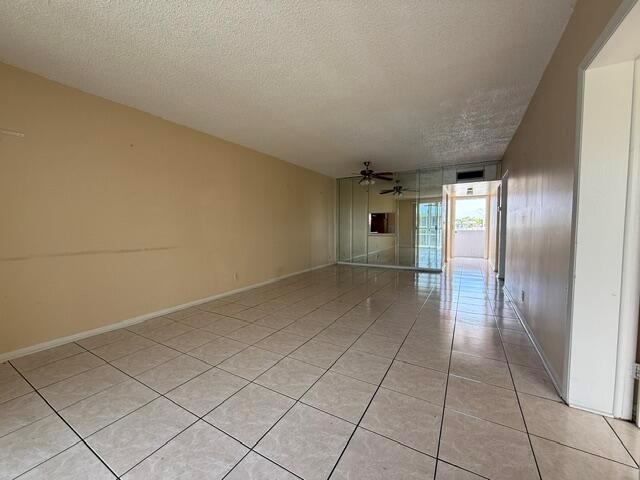 A living room features beige tile floors, a light-colored sofa, and a mirrored accent wall — 6005 Del Lago Circle # 305, Sunrise FL 33313, SUNRISE, FL
