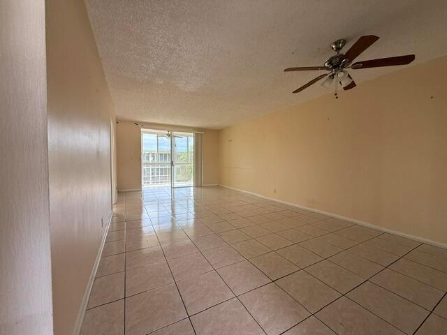 An empty room with beige tile flooring, plain walls, and a mirrored wall section — 6005 Del Lago Circle # 305, Sunrise FL 33313, SUNRISE, FL