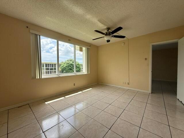An empty room with beige walls, tiled flooring, a ceiling fan, and a large window — 6005 Del Lago Circle # 305, Sunrise FL 33313, SUNRISE, FL