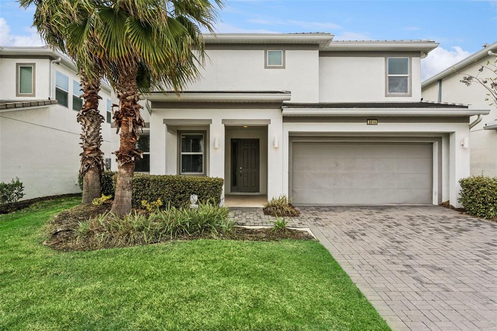 A two-story house with a paved driveway, a two-car garage, and a palm tree — 2614 CALISTOGA AVENUE, KISSIMMEE, FL