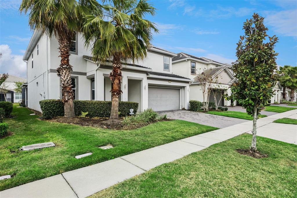 A two-story suburban house with a paved driveway, palm trees, and a green lawn — 2614 CALISTOGA AVENUE, KISSIMMEE, FL