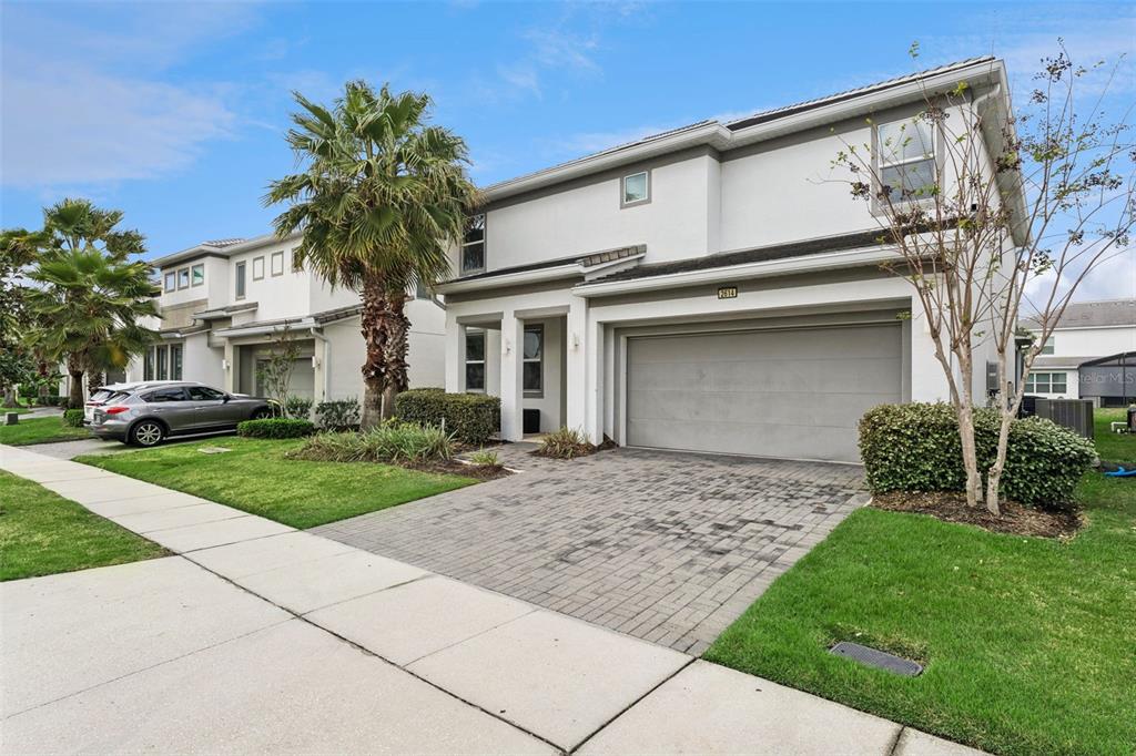 A two-story suburban house with a paved driveway, a two-car garage, and a palm tree — 2614 CALISTOGA AVENUE, KISSIMMEE, FL