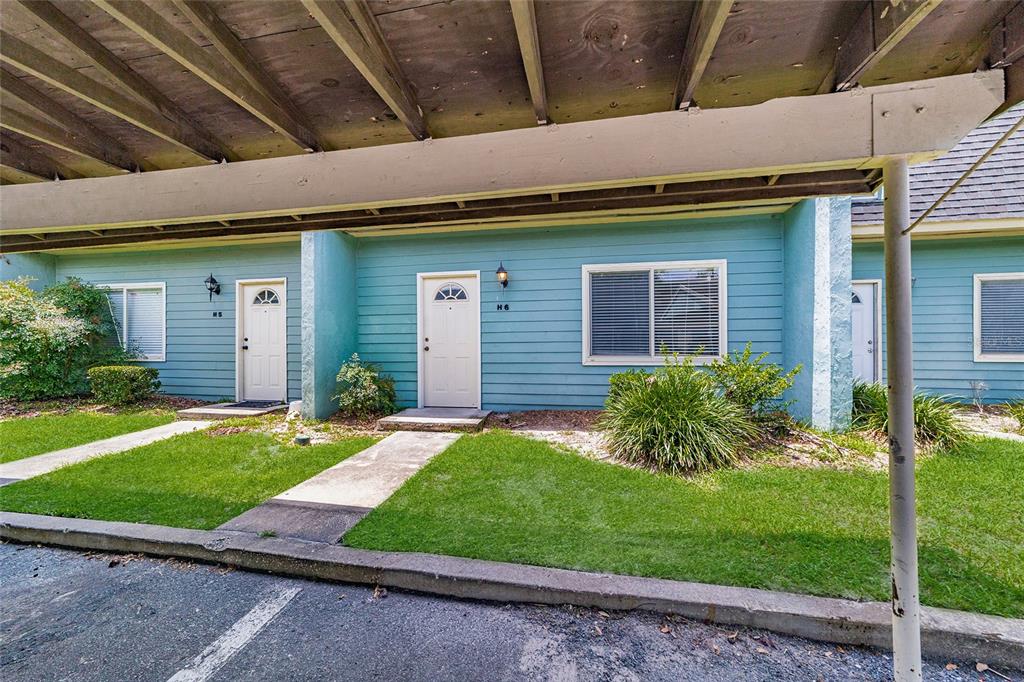 The exterior of a blue-sided residential building features two white doors under a covered walkway — 501 SW 75TH STREET UNIT H6, GAINESVILLE, FL