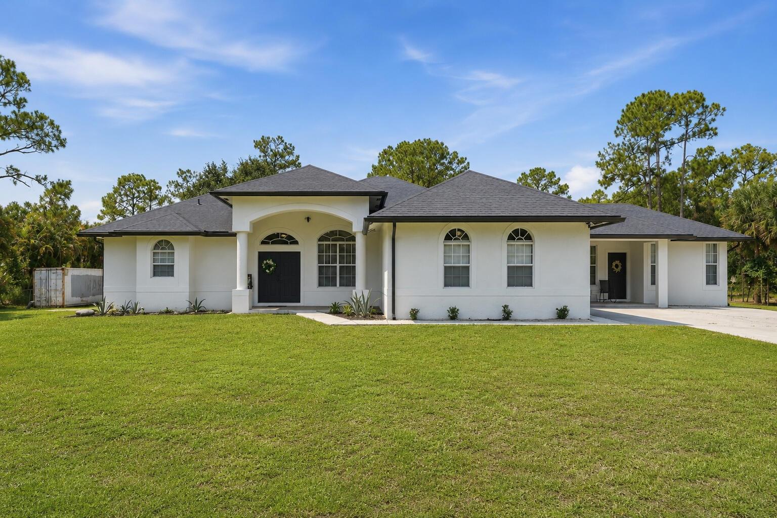 A white, single-story house with a dark roof, arched windows, and a covered front entryway — 18220 N 90th St Street N, FL 33470, FL