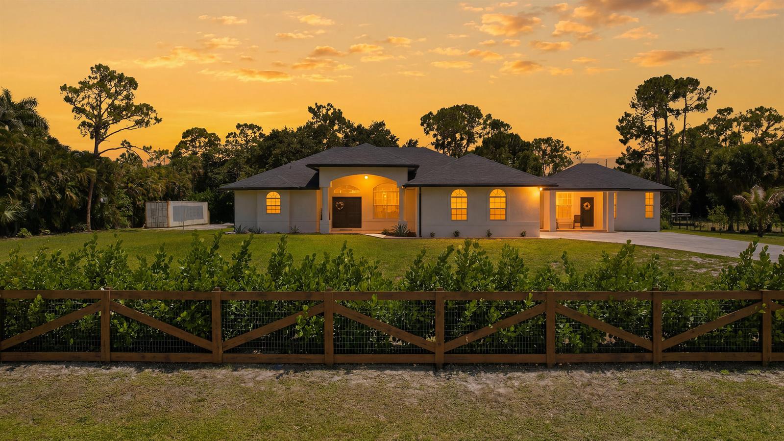 A single-story house with a wooden fence in the foreground under a sunset sky — 18220 N 90th St Street N, FL 33470, FL